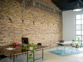 Schreibtisch mit Fensterfront und Backsteinwand
