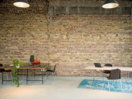 Schreibtisch mit Fensterfront und Backsteinwand
